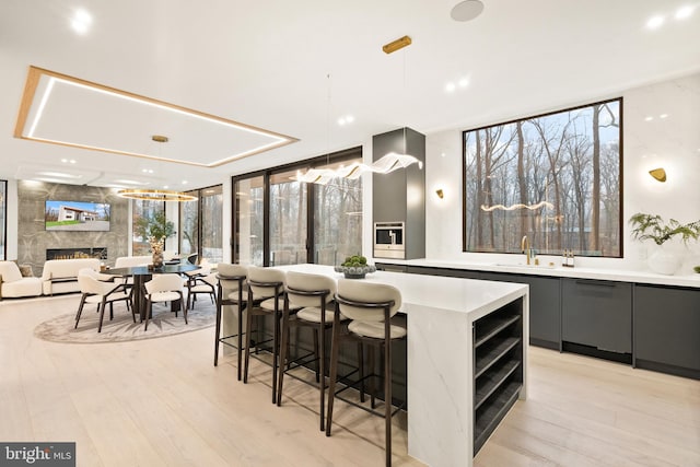 kitchen featuring expansive windows, light countertops, a kitchen island, modern cabinets, and a sink