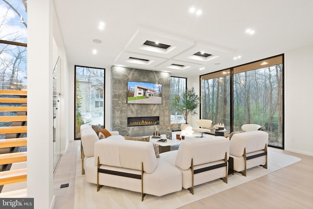 living room featuring a wealth of natural light, coffered ceiling, a high end fireplace, and expansive windows