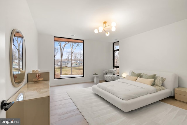 bedroom with a chandelier, wood finished floors, and visible vents