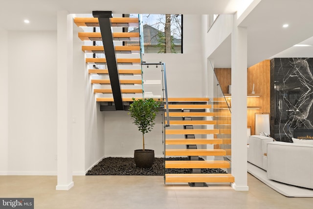 staircase with recessed lighting, a fireplace, and baseboards