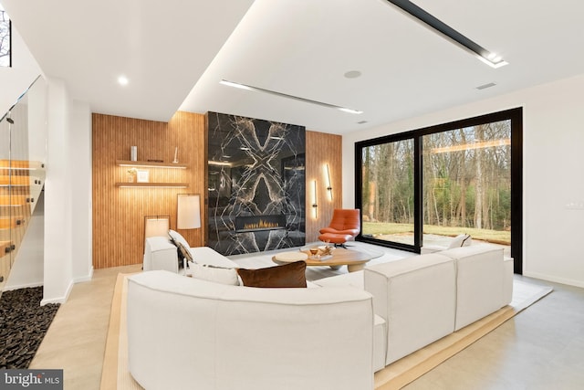 living area featuring visible vents, baseboards, a high end fireplace, stairs, and wood walls