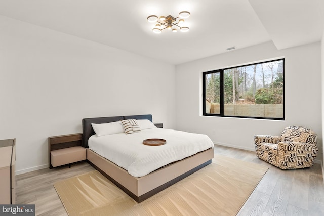 bedroom with light wood finished floors, baseboards, and visible vents