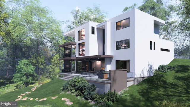 rear view of property with a yard, a balcony, and stucco siding