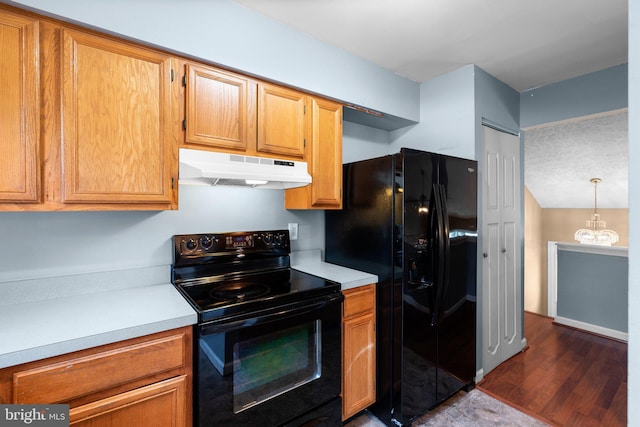 6011 Bauman Dr, Elkridge, MD 21075 - kitchen with dark wood-style flooring, under cabinet range hood, black appliances, light countertops, and a notable chandelier