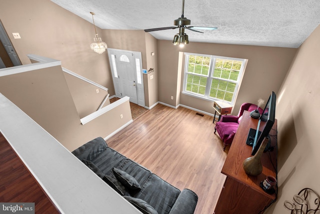 6011 Bauman Dr, Elkridge, MD 21075 - living area featuring vaulted ceiling, wood finished floors, a textured ceiling, ceiling fan with notable chandelier, and baseboards