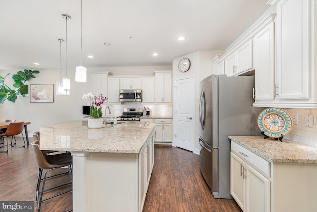 kitchen with dark wood-style flooring, a breakfast bar, white cabinetry, backsplash, and appliances with stainless steel finishes