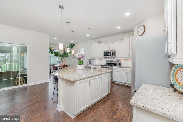 kitchen with dark wood-style flooring, a sink, white cabinetry, stainless steel appliances, and pendant lighting