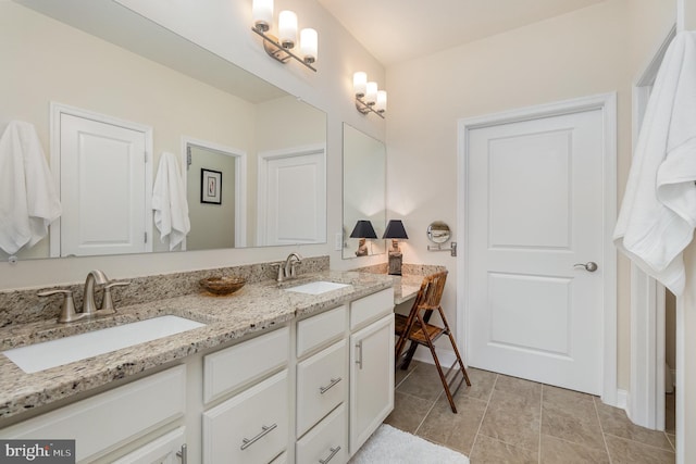 full bath featuring double vanity, baseboards, and a sink