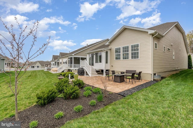 back of house featuring a sunroom, a patio, a yard, and an outdoor fire pit