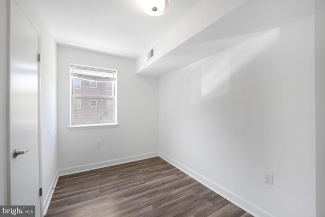 empty room featuring baseboards, visible vents, and dark wood finished floors