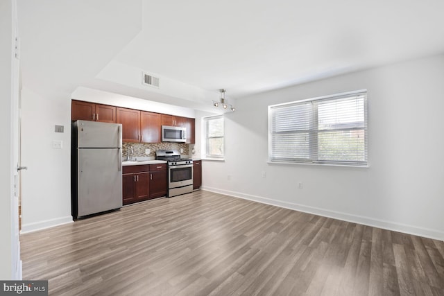 kitchen with stainless steel appliances, baseboards, visible vents, backsplash, and light wood-style floors