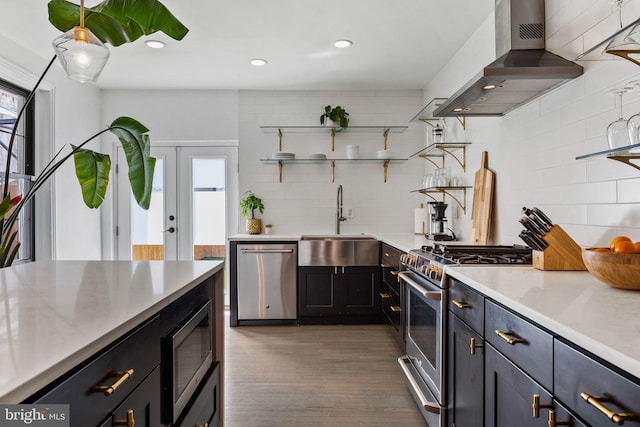 kitchen featuring a sink, wall chimney exhaust hood, appliances with stainless steel finishes, and plenty of natural light