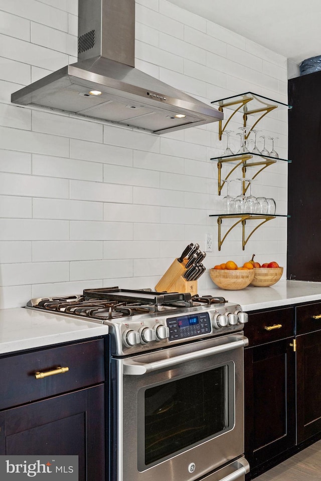kitchen featuring wall chimney exhaust hood, backsplash, stainless steel gas stove, and light countertops
