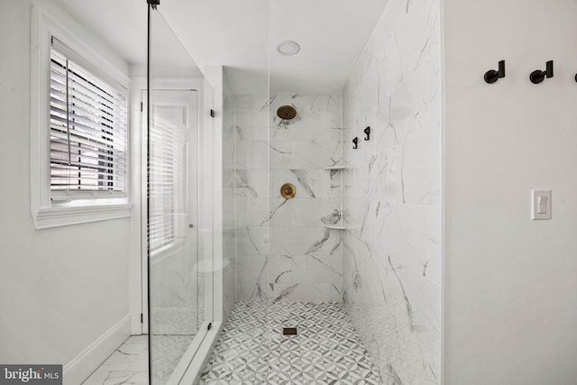 bathroom featuring a marble finish shower, marble finish floor, and baseboards