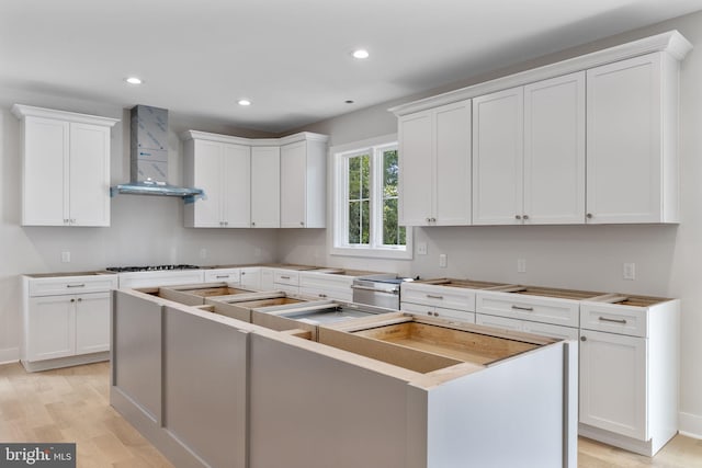 17 Hickory Ln, Malvern, PA 19355 - kitchen with wall chimney range hood, a kitchen island, white cabinets, light wood-style floors, and gas stovetop