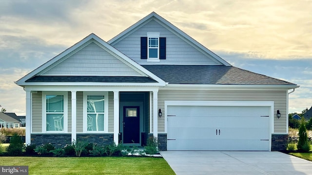 craftsman inspired home with stone siding, a garage, a front lawn, driveway, and roof with shingles