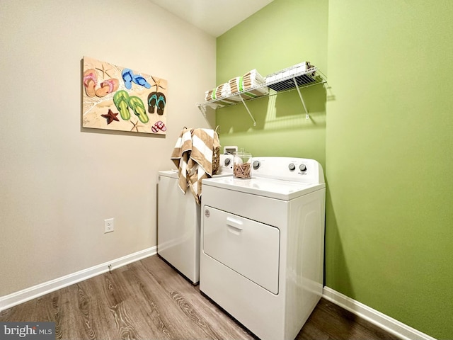 laundry area featuring laundry area, wood finished floors, baseboards, and washer and clothes dryer