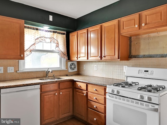 kitchen featuring tasteful backsplash, white appliances, light stone countertops, brown cabinets, and a sink