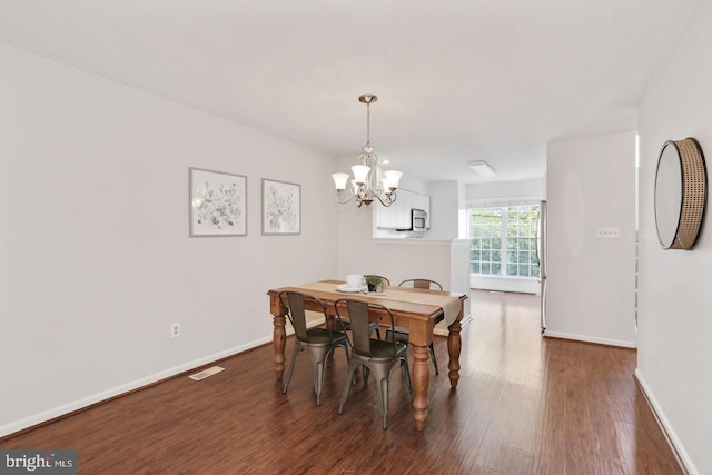dining room with baseboards, a notable chandelier, wood finished floors, and visible vents
