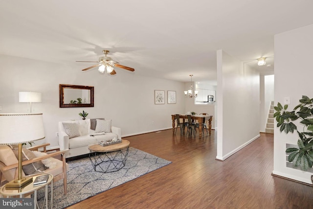 living area with stairway, baseboards, ceiling fan with notable chandelier, and wood finished floors