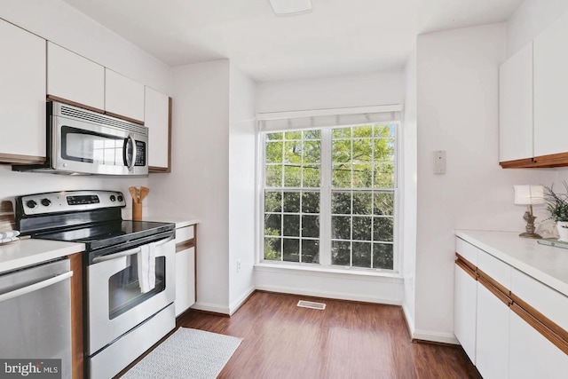 kitchen with light countertops, appliances with stainless steel finishes, white cabinets, and visible vents