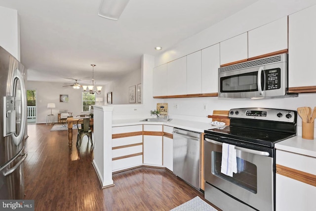 kitchen with light countertops, a peninsula, white cabinets, and stainless steel appliances