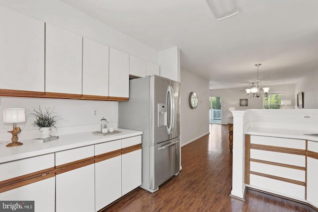 kitchen featuring pendant lighting, light countertops, stainless steel fridge, an inviting chandelier, and white cabinetry