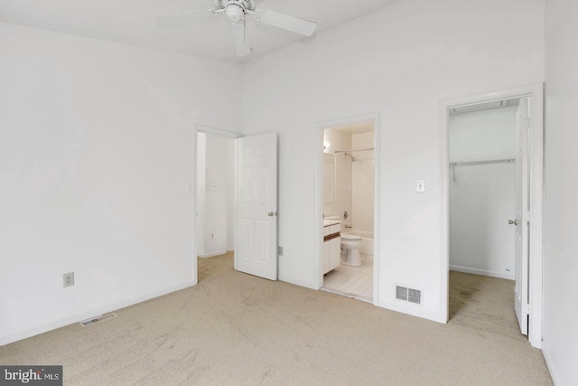 unfurnished bedroom with light colored carpet, visible vents, and a walk in closet