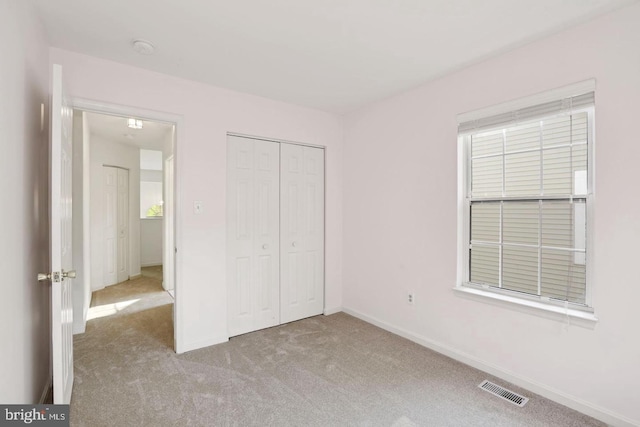unfurnished bedroom with baseboards, visible vents, carpet, and a closet