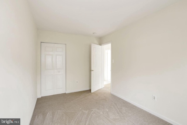 unfurnished bedroom featuring baseboards, carpet, and a closet