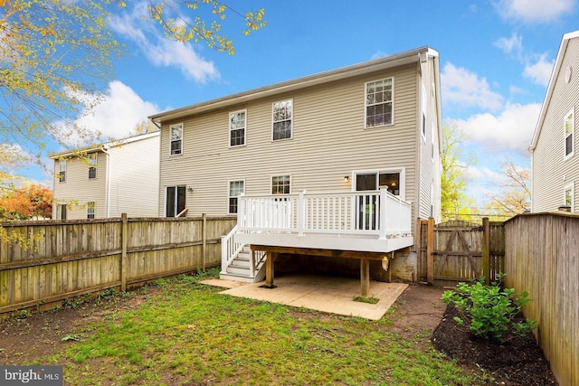 back of property with a deck, a gate, and a fenced backyard