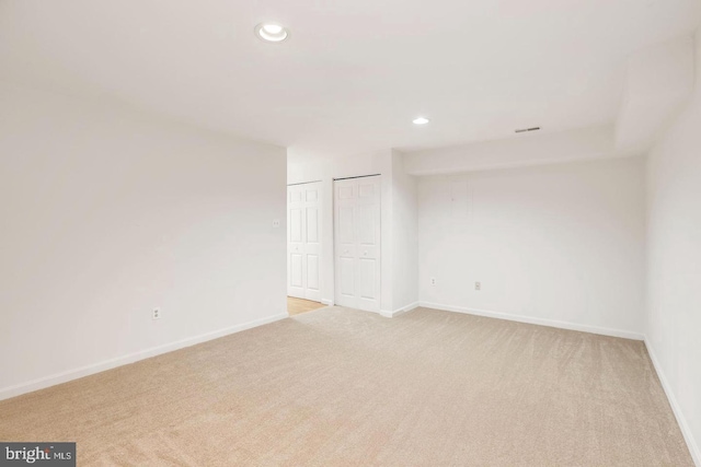 empty room with light colored carpet, recessed lighting, and baseboards