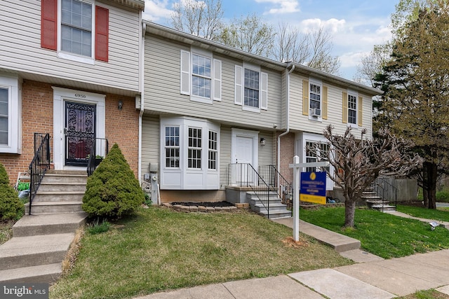 townhome / multi-family property featuring brick siding and a front lawn