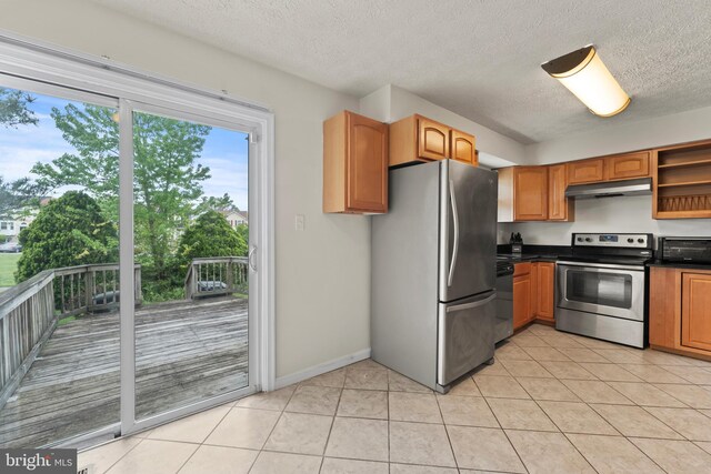 10633 Campus Way S, Upper Marlboro, MD 20774 - kitchen featuring a textured ceiling, dark countertops, appliances with stainless steel finishes, under cabinet range hood, and light tile patterned floors