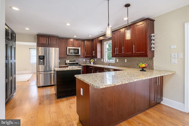 kitchen with stainless steel appliances, a peninsula, light wood-type flooring, tasteful backsplash, and baseboards