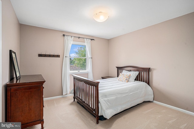 bedroom with light colored carpet and baseboards