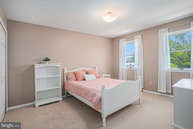 bedroom with light carpet and baseboards