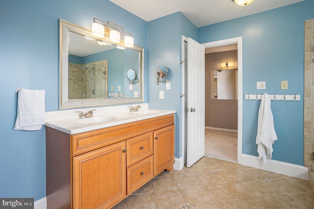 full bath with a tile shower, tile patterned floors, double vanity, and baseboards
