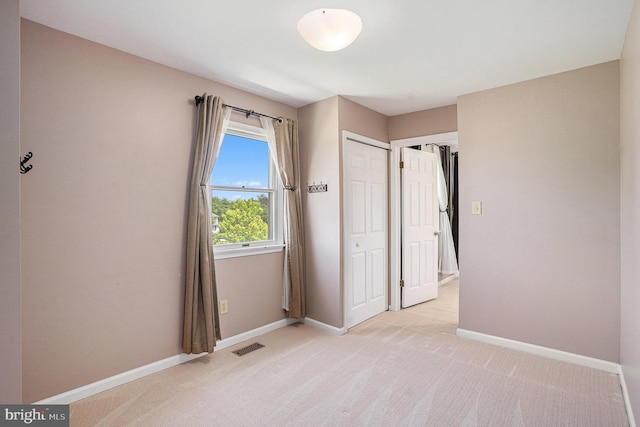 unfurnished bedroom featuring baseboards, light colored carpet, and a closet
