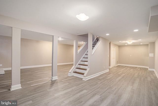 finished basement with light wood-style floors, stairs, baseboards, and recessed lighting