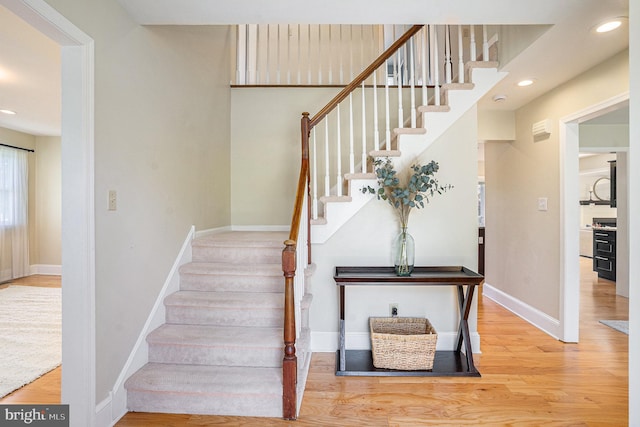 stairs with baseboards, wood finished floors, and recessed lighting