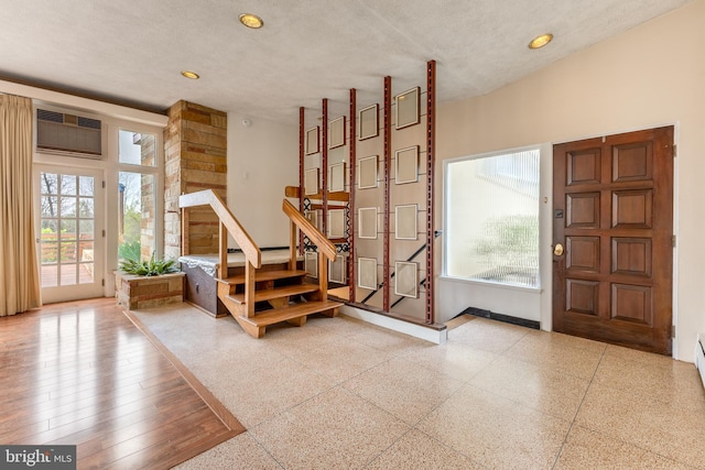 foyer entrance with recessed lighting, a wall unit AC, and a wealth of natural light