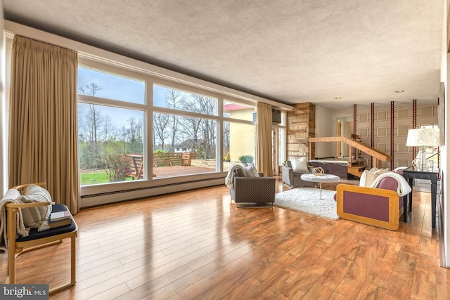 living room with a baseboard radiator, wood finished floors, and a healthy amount of sunlight