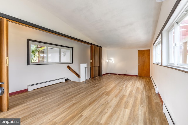 spare room with a baseboard radiator, light wood finished floors, and baseboards