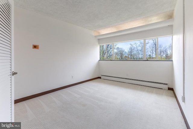 spare room with baseboards, light carpet, a baseboard heating unit, and a textured ceiling