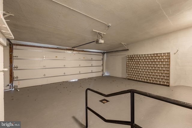 garage featuring concrete block wall and a garage door opener