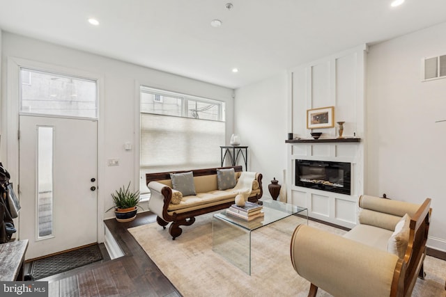 living room featuring a glass covered fireplace, wood finished floors, visible vents, and recessed lighting