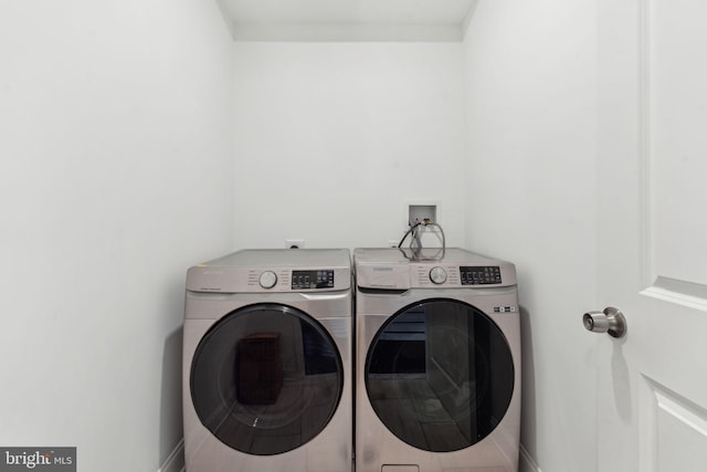 washroom with washing machine and clothes dryer, laundry area, and baseboards