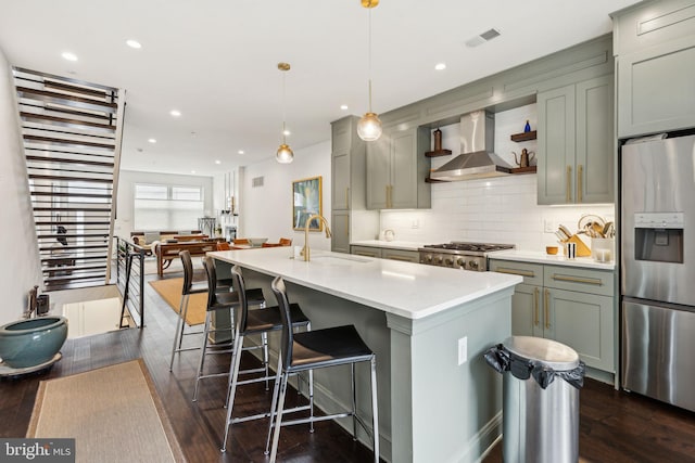 kitchen featuring a sink, stainless steel fridge, light countertops, wall chimney exhaust hood, and visible vents
