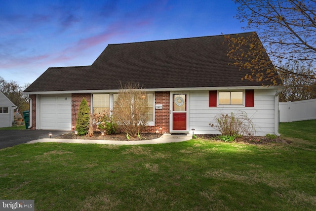 cape cod-style house with aphalt driveway, fence, a shingled roof, a lawn, and a garage